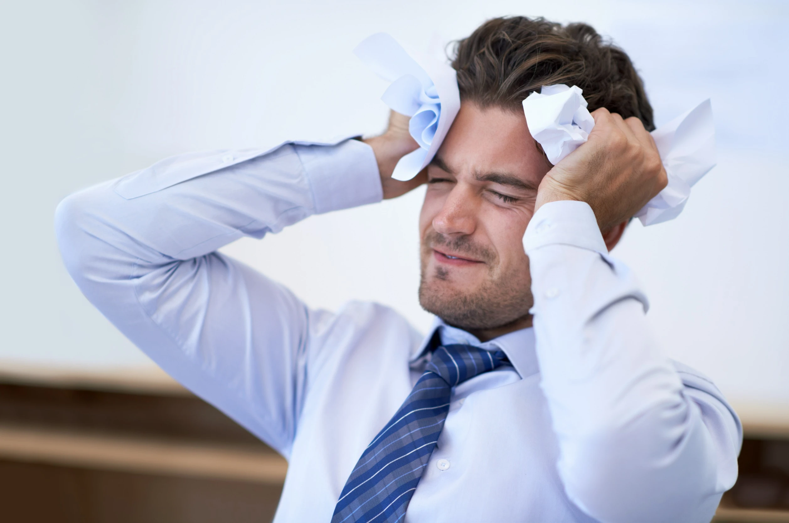 Natural Life Acupuncture and Wellness A man sitting with his hands on his head, looking distressed and suffering from a headache due to stress.